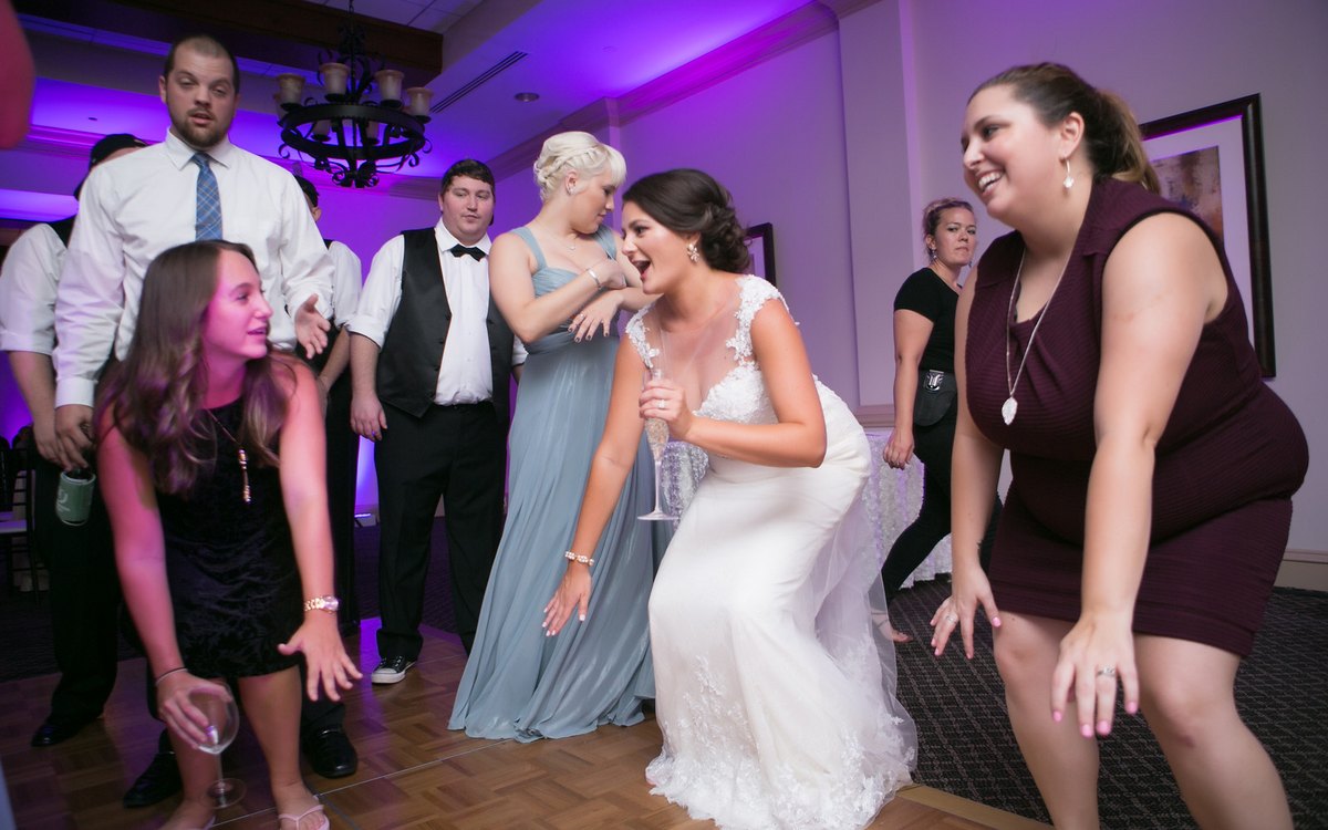 Guests dancing under purple ATG uplighting at a wedding at Ballantyne Country Club