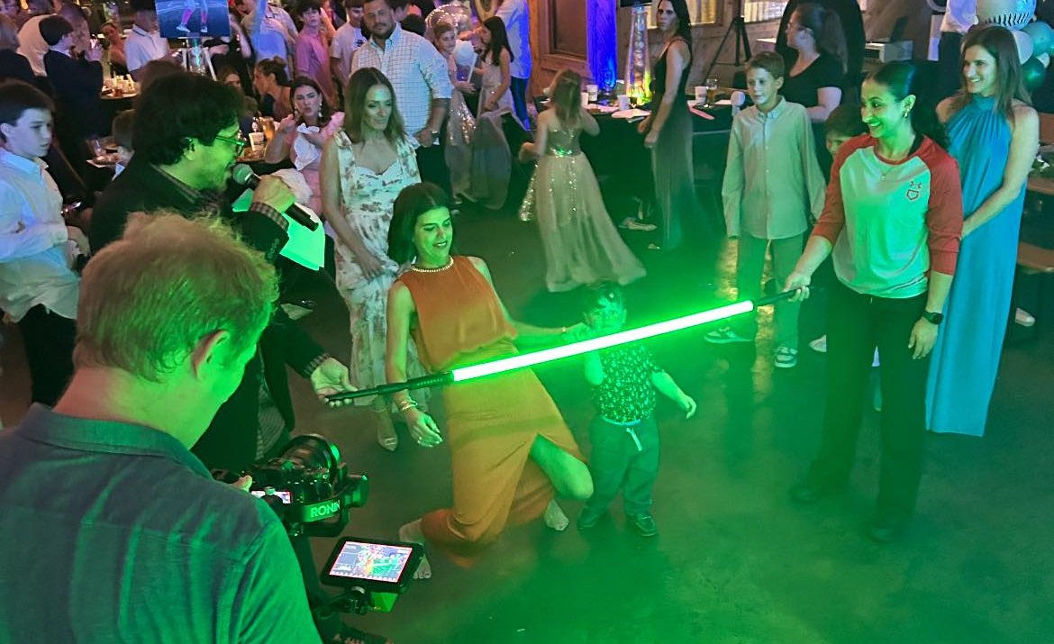 Teens playing LED glow limbo on a crowded dance floor