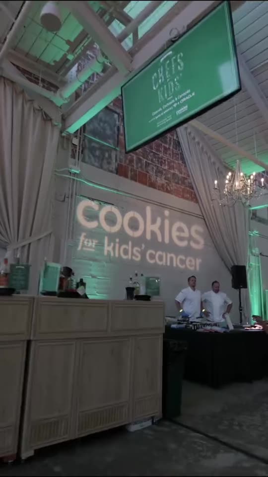 Custom Cookies for Kids' Cancer logo projected on a wall with event screens