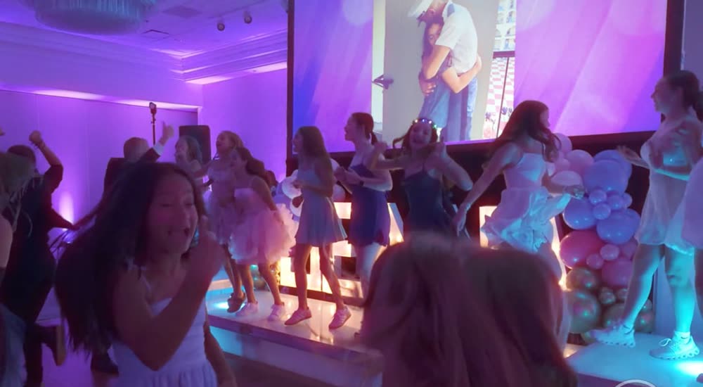 Girls dancing at a Bat Mitzvah under purple and pink lights