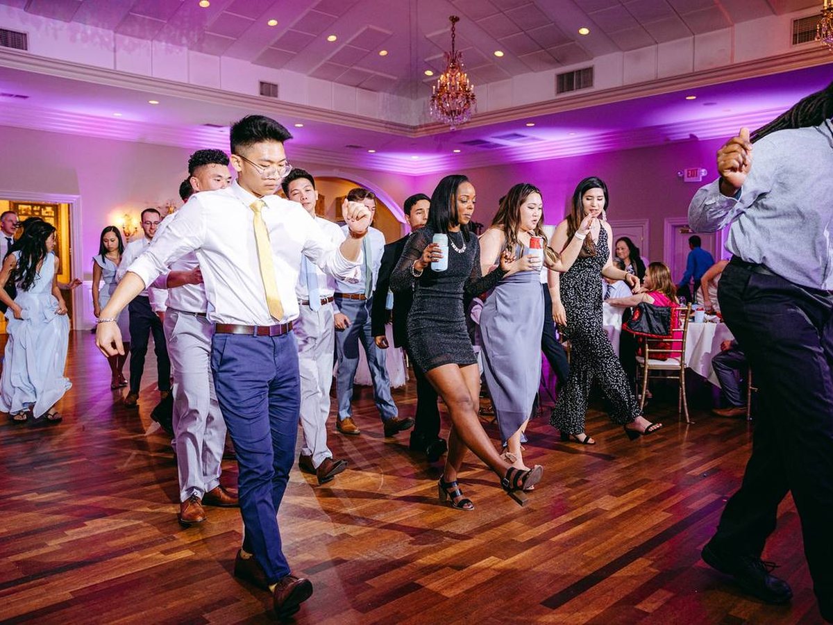 A full dance floor under the Magnolia Room chandeliers, with purple ATG uplighting, at Andrew's wedding